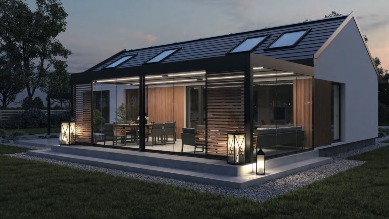 Moderner Kaltwintergarten aus Aluminium in Anthrazit mit rahmenlosen Glas-Schiebetüren, seitlichen Shutters als Sonnenschutz und warmer LED-Beleuchtung bei Nacht.