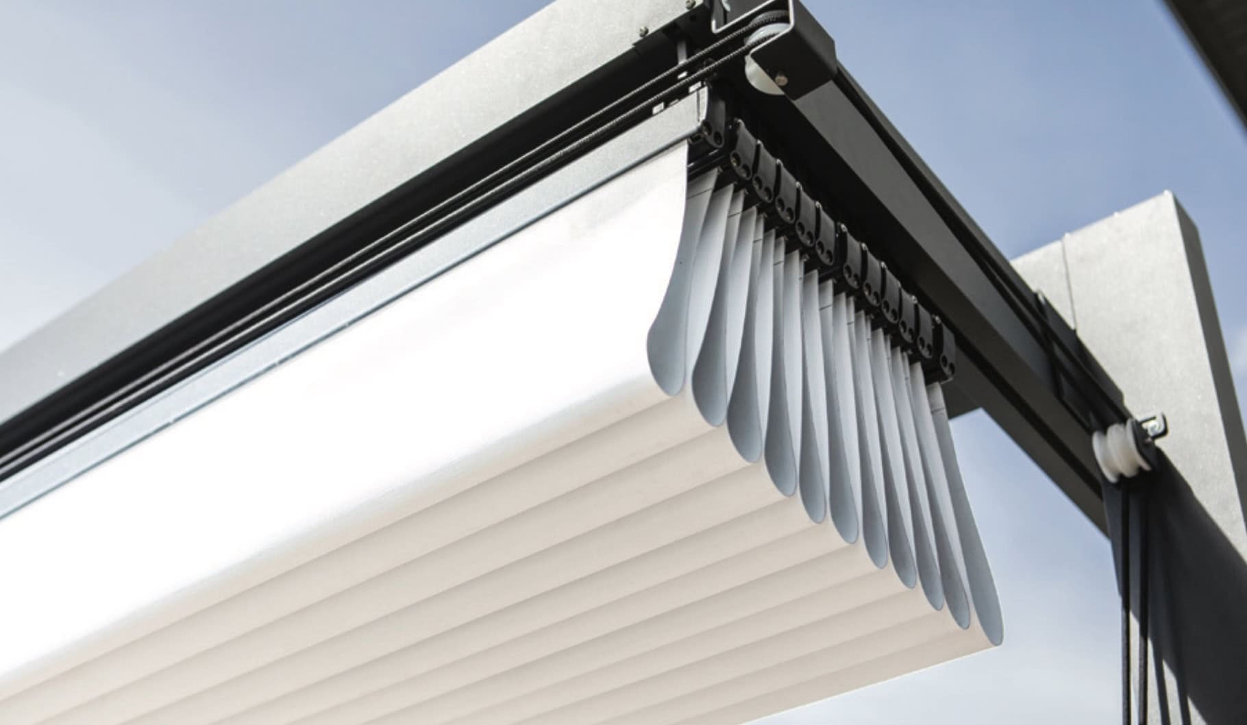 Technische Detailansicht der robusten Aluminium-Führungsschienen und Laufwagen einer hochwertigen Pergola-Markise für langlebigen Sonnenschutz.