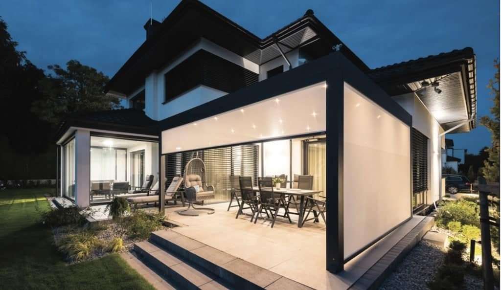 Beleuchteter Kaltwintergarten am Abend, der mit geschlossenen ZIP-Screens eine gemütliche, herbstfeste Terrasse schafft.